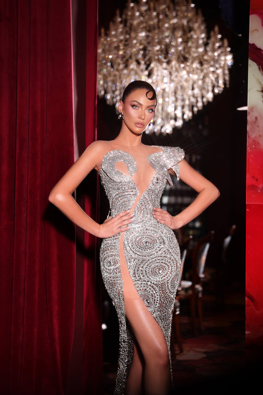 Woman in a silver evening gown with a chandelier in the background