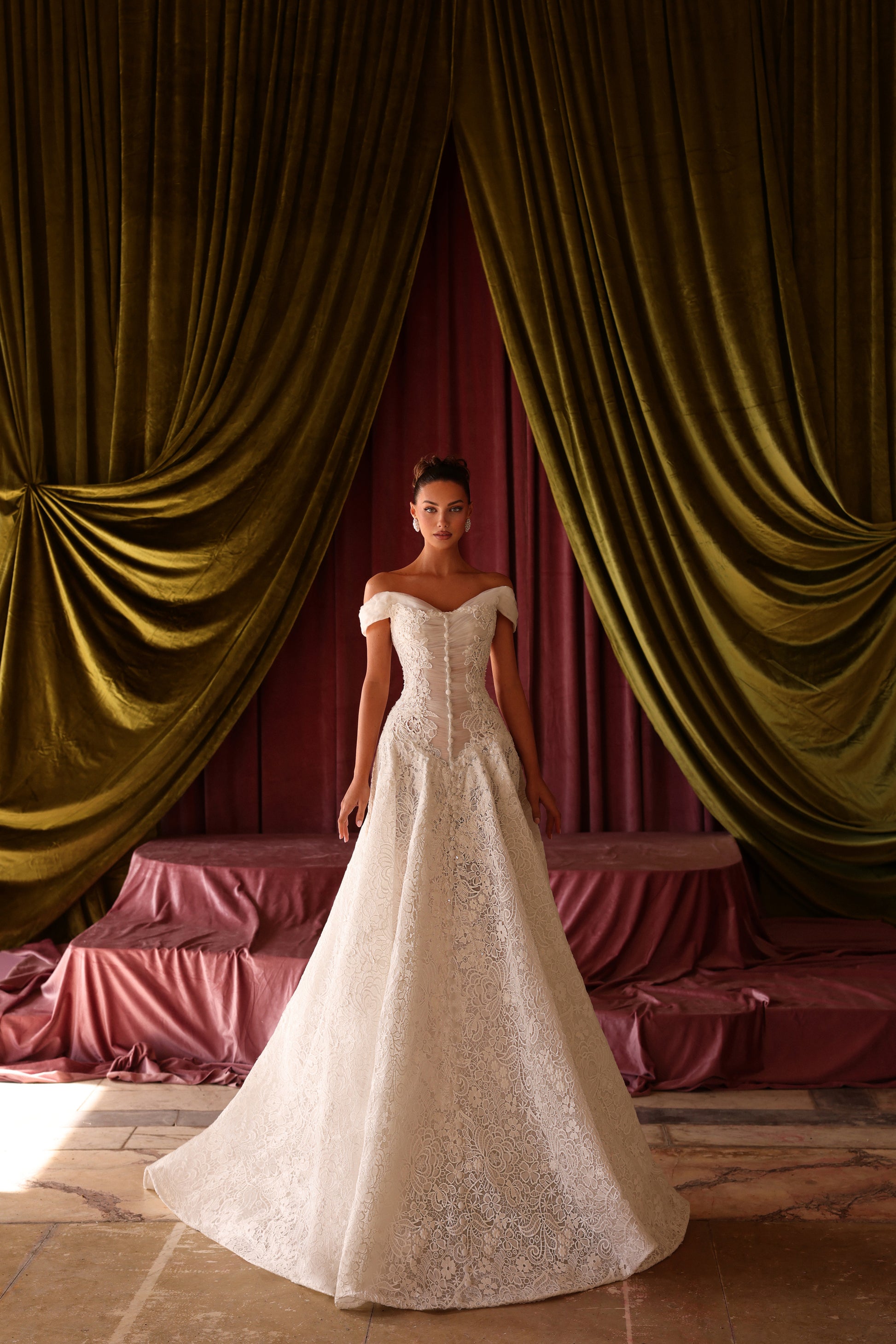 Woman in a white wedding dress standing in front of gold curtains