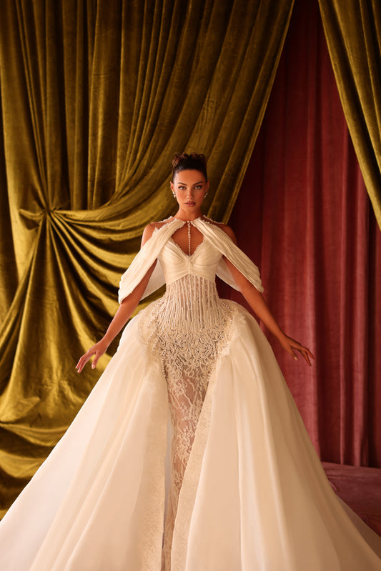 Woman in a white wedding dress standing in front of red and gold draped curtains