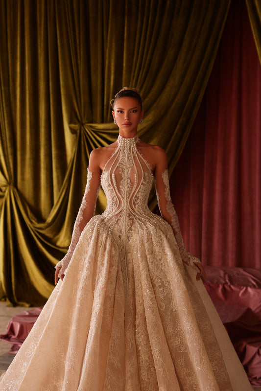 Woman in a beige wedding dress with intricate detailing against draped fabric.