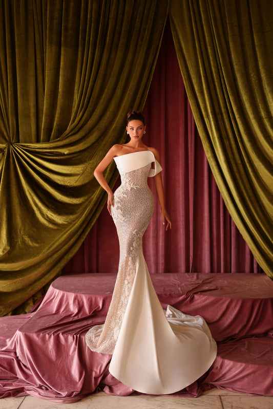 Woman in a white gown standing in front of draped curtains