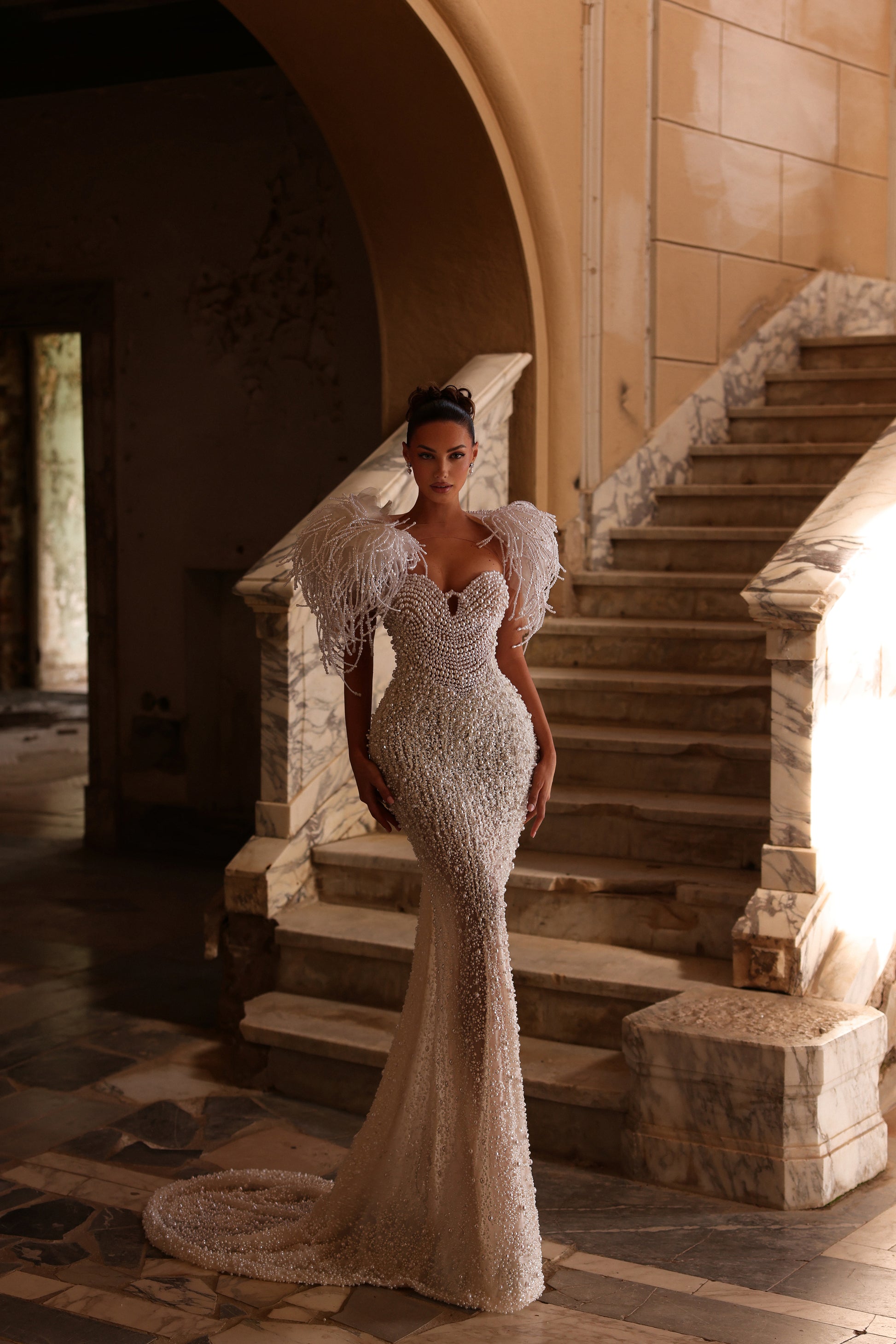 Woman in a sparkling evening gown standing on a staircase in an elegant interior setting