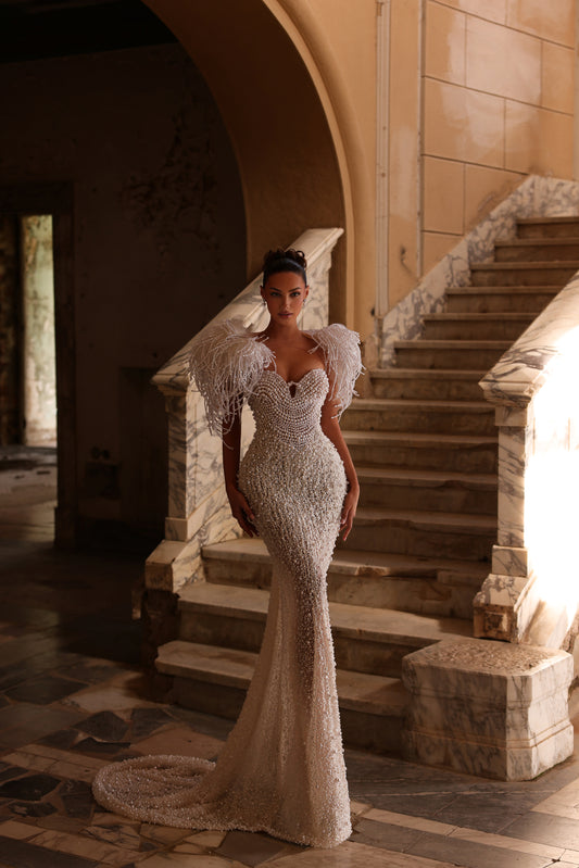Woman in a sparkling evening gown standing on a staircase in an elegant interior setting